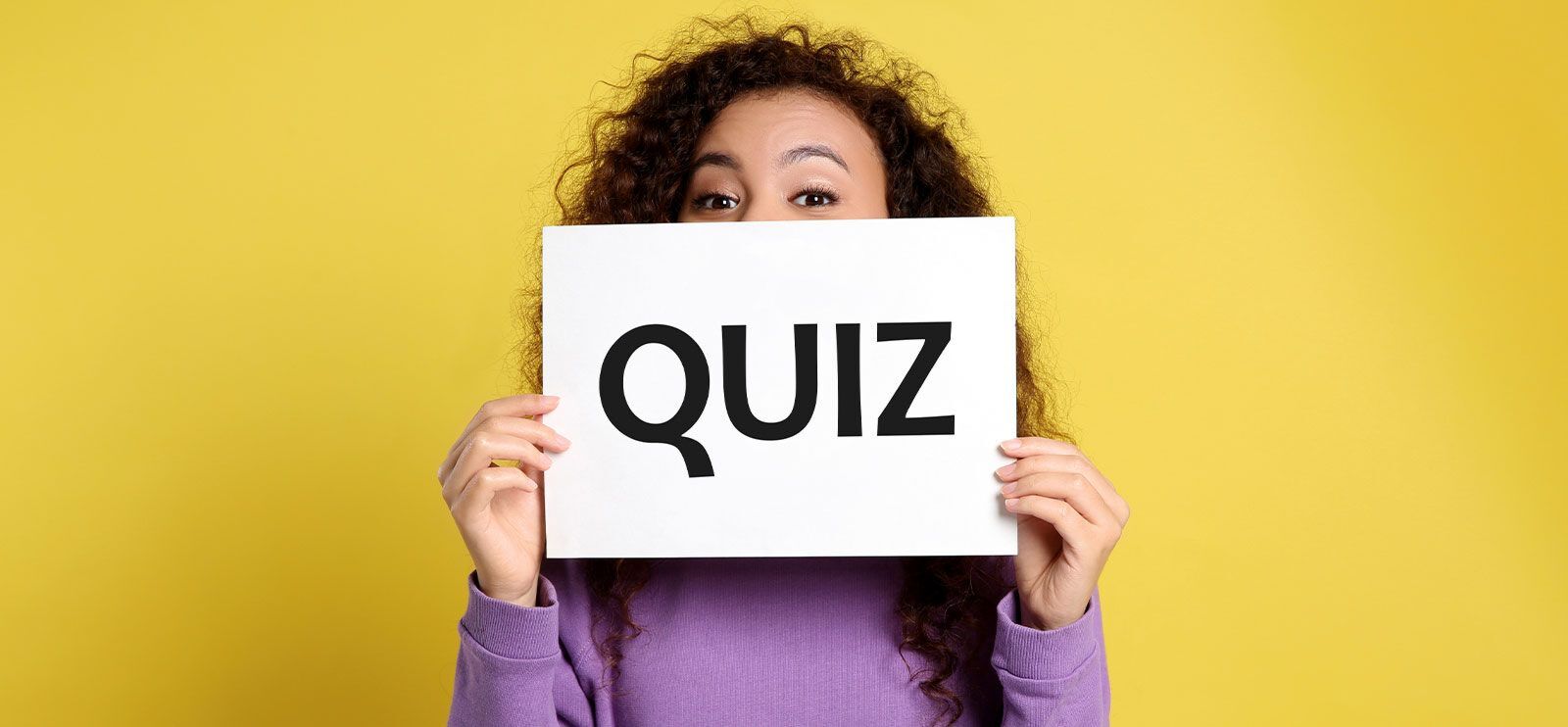 Kvinne med mørkt hår og brune øyne holder et ark der det står "quiz". Hun har lilla genser og bakgrunnen er gul.