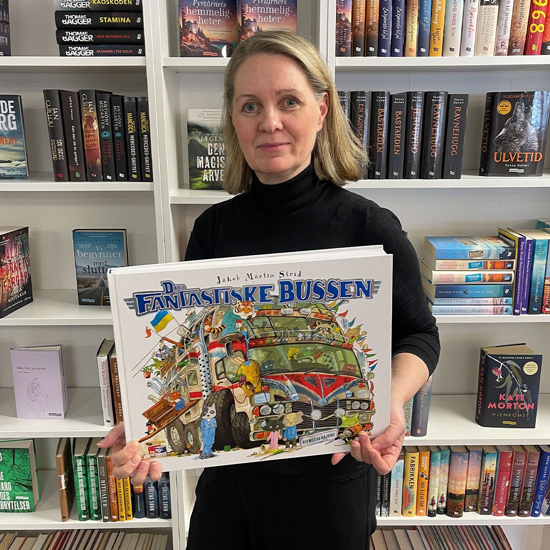 Gunn Schmidt, forlagsredaktør, holder den store barneboken Den fantastiske bussen.