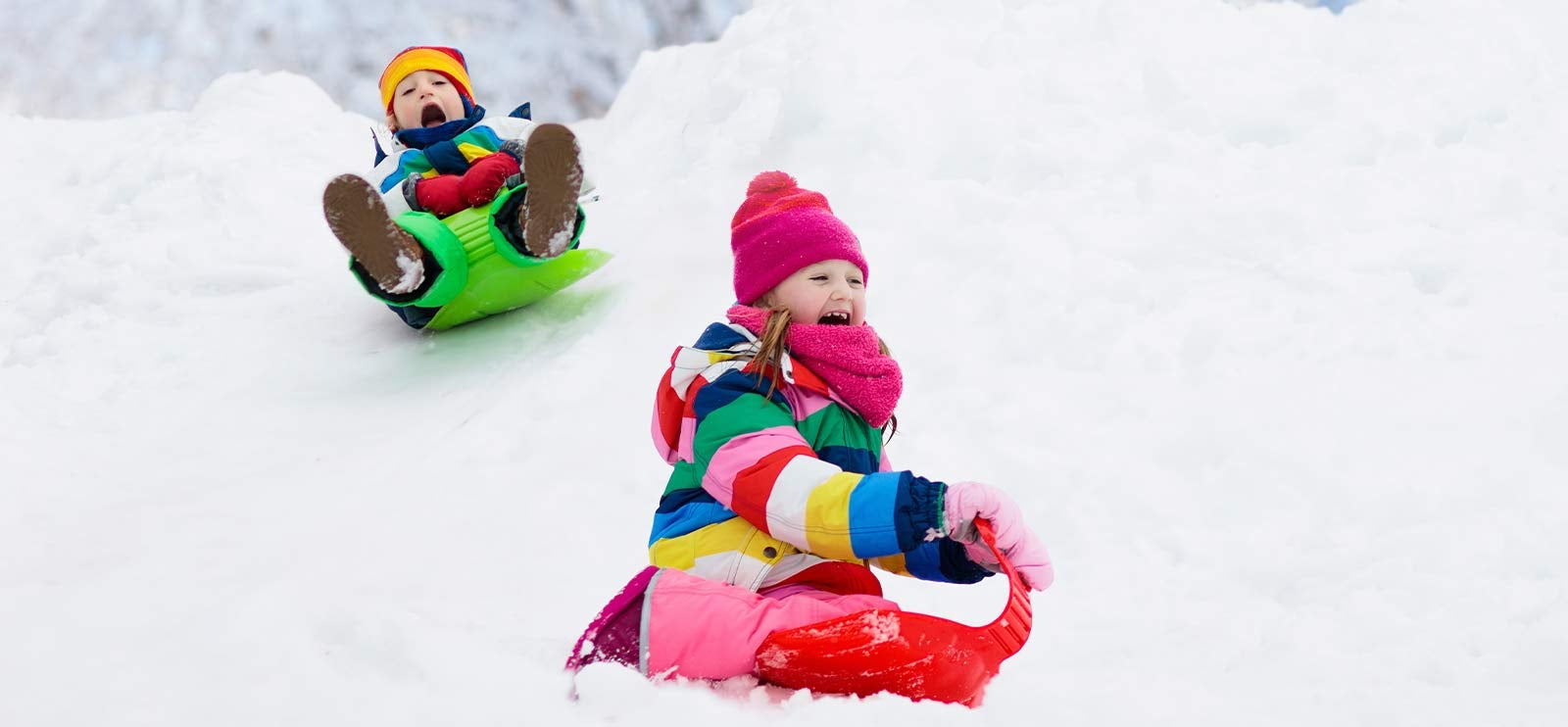 To barn som leker i snøen med rumpeakebrett.