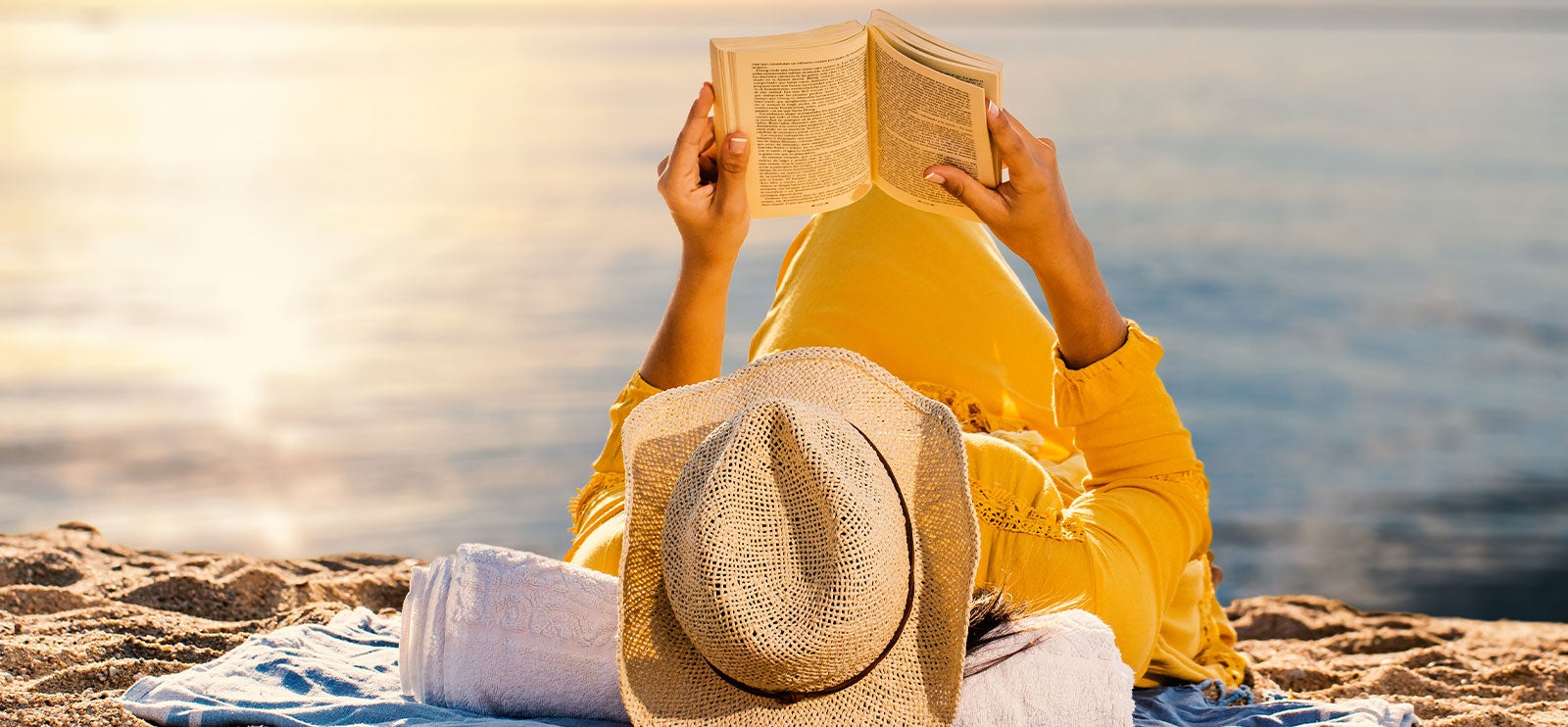 Kvinne leser bok på stranden